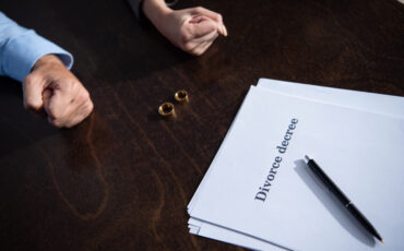 view of couple with clenched fists sitting at table with rings