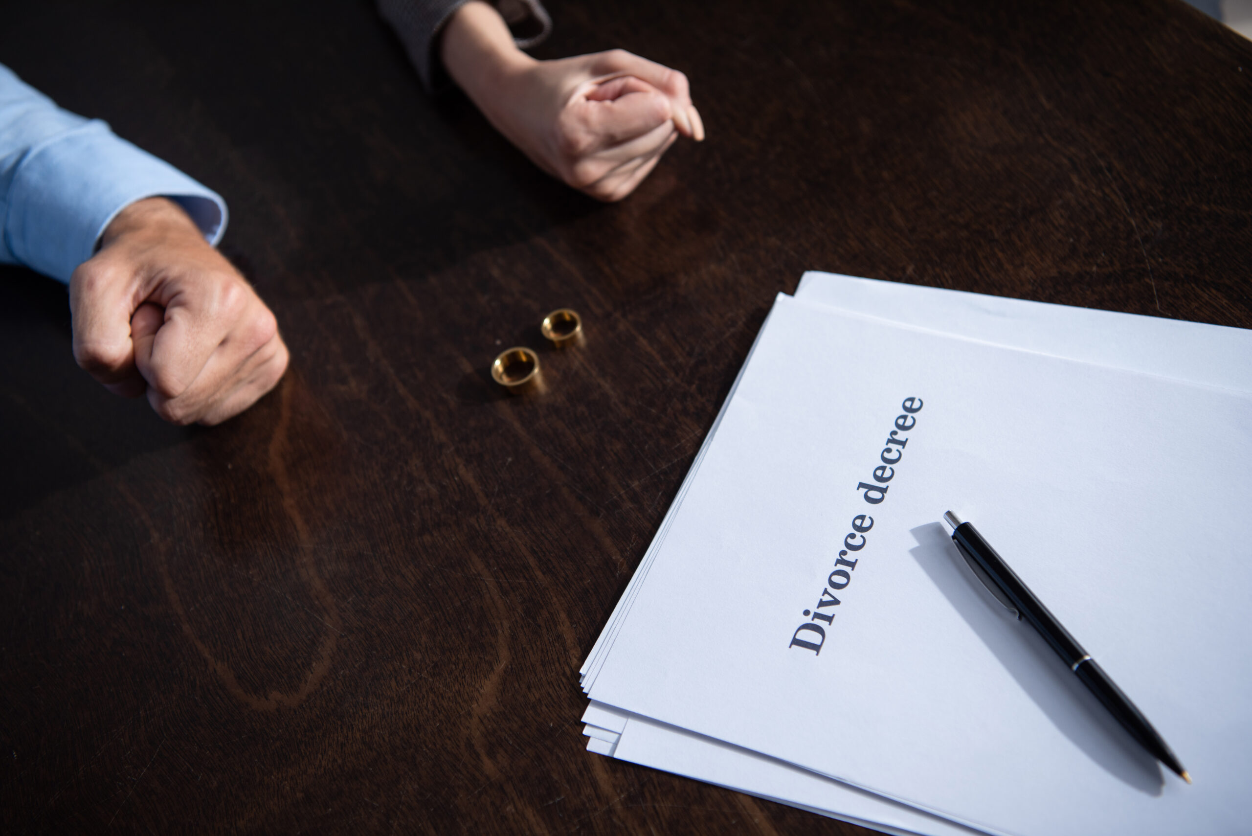 view of couple with clenched fists sitting at table with rings