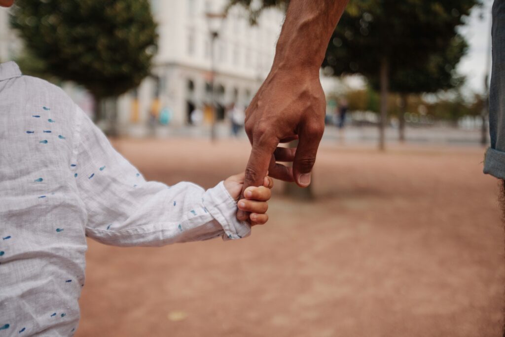 A child holding his father’s hand, representing the child's rights post paternity establishment.